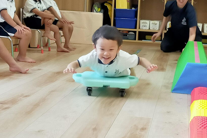 台車で滑る遊びをする子ども